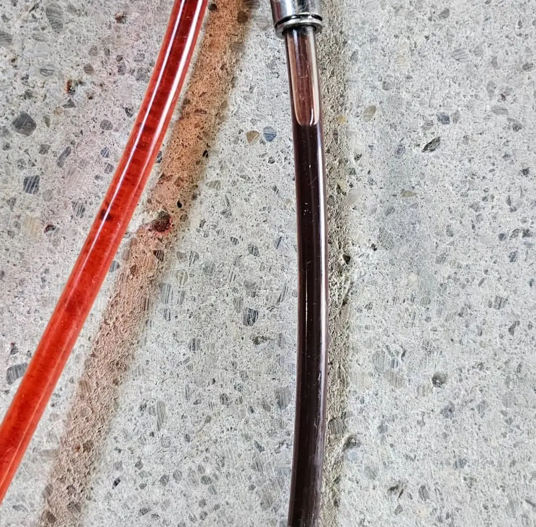 Zwei Schläuche im Vergleich, links das rote Frischöl, rechts das dunkelbraune Altöl