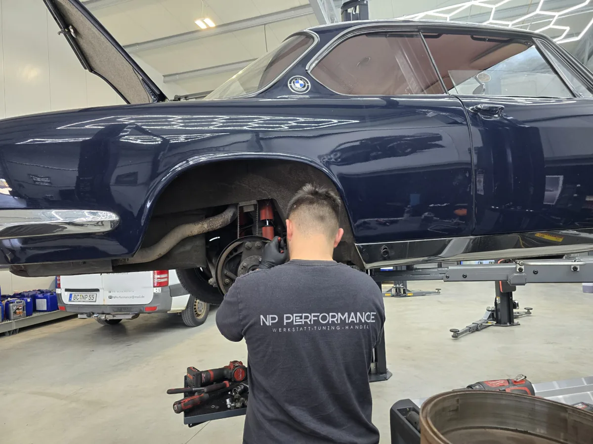 Mechaniker im NP-Performance-Shirt arbeitet an der Hinterachse eines BMW E9