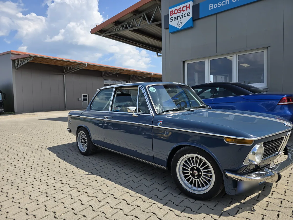 Blauer BMW 2002 vor dem Bosch-Car-Service-Schild der Werkstatt