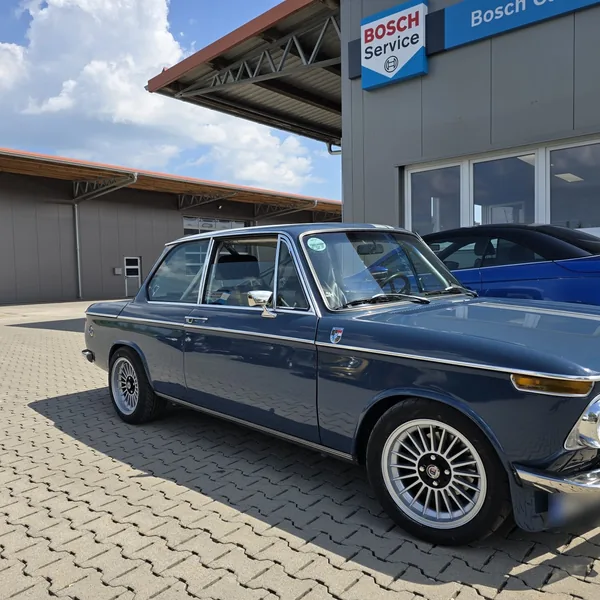 Blauer BMW 2002 vor dem Bosch-Car-Service-Schild der Werkstatt