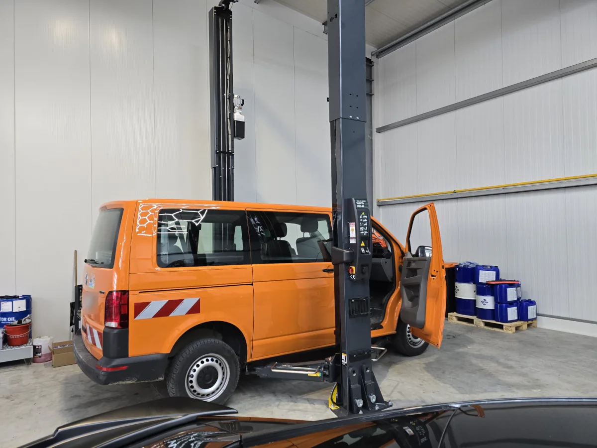 Oranger VW T6 Transporter mit Warnmarkierung auf der Hebebühne, Fahrertür geöffnet